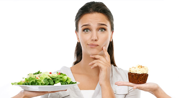 Studio shot of a young woman choosing between a healthy and unhealthy diet